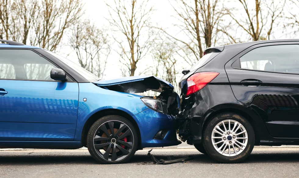 Two cars involved in a rear-end collision on the road, showing visible front and back-end damage.